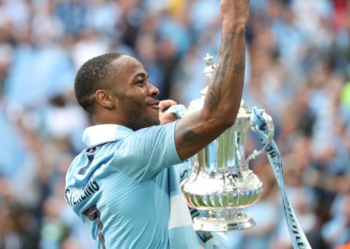 Raheem Sterling with Manchester City celebrates with the FA Cup Trophy in 2019