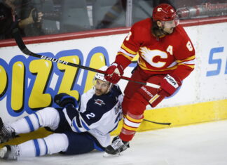 Winnipeg Jets' Dylan DeMelo, left, is checked by Calgary Flames' Chris Tanev during third period NHL pre-season hockey action in Calgary in October 2021