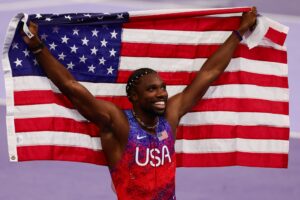 Noah Lyles of USA wins Gold and celebrates with the USA flag during the Men's 100m Final Paris 2024 Olympic Games in August 2024