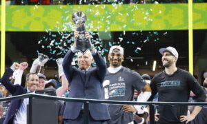 Philadelphia Eagles owner Jeffrey Lurie is presented the Vince Lombardi Trophy as quarterback Jalen Hurts and head coach Nick Sirianni look on during celebrations after the Eagles defeated the Chiefs 40-22 in Super Bowl LIX at Caesars Superdome in New Orleans on Sunday, February 9, 2025